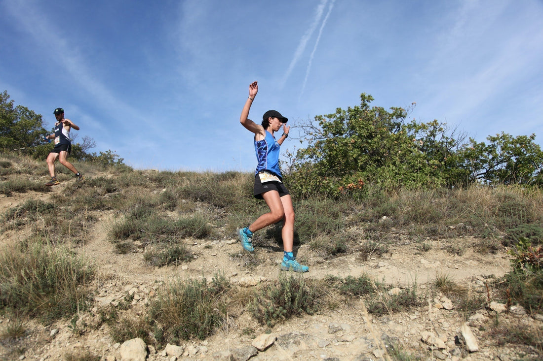 Picture of two trail runners running down a dirt path on a sunny day