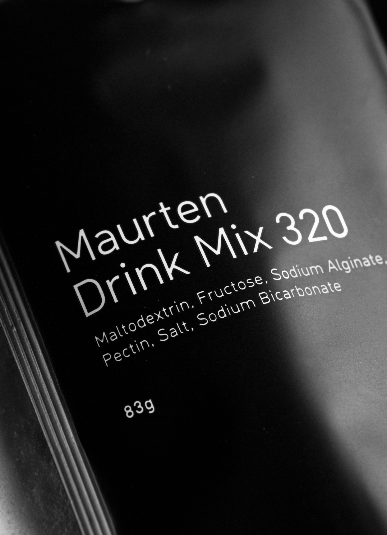A close-up of a single packet of Maurten Fuel Drink Mix 320, primarily in black color with white text detailing the product name and ingredients.