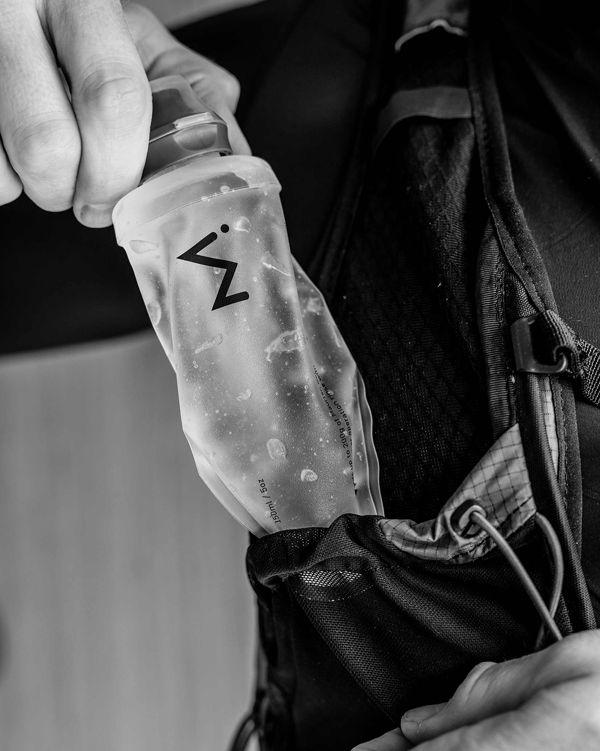 Person putting a Maurten GelFlask 150 ml in a hydration vest pocket