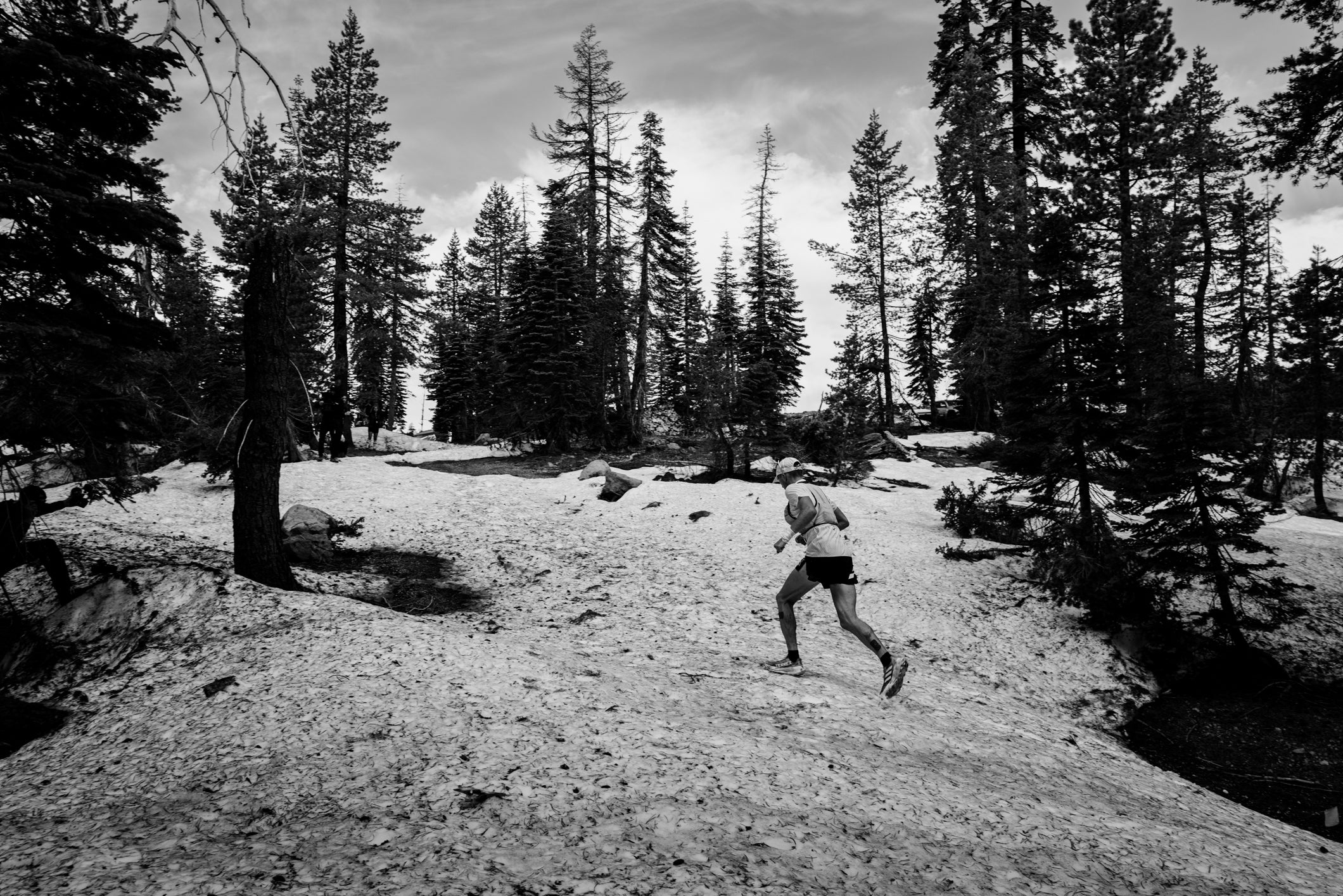 Black and white picture of a trail runner running up a hill