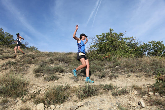 Picture of two trail runners running down a dirt path on a sunny day