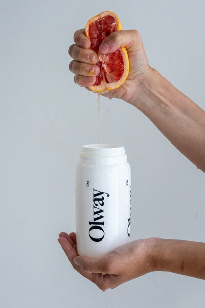 Hand squeezing fresh grapefruit into Olway Performance Drink Mix for a custom-flavoured, unflavoured endurance hydration drink