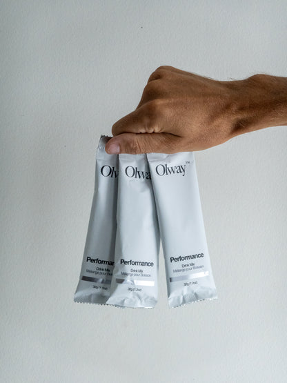 Hand holding three Olway Performance Drink Mix 32 g single-serve packets, ready to include in a Fuel Kit for portable endurance hydration and energy