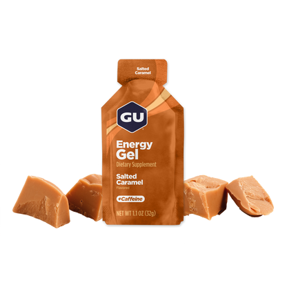 A packet of GU Energy Gel in Salted Caramel flavor, with visible pieces of caramel beside it.