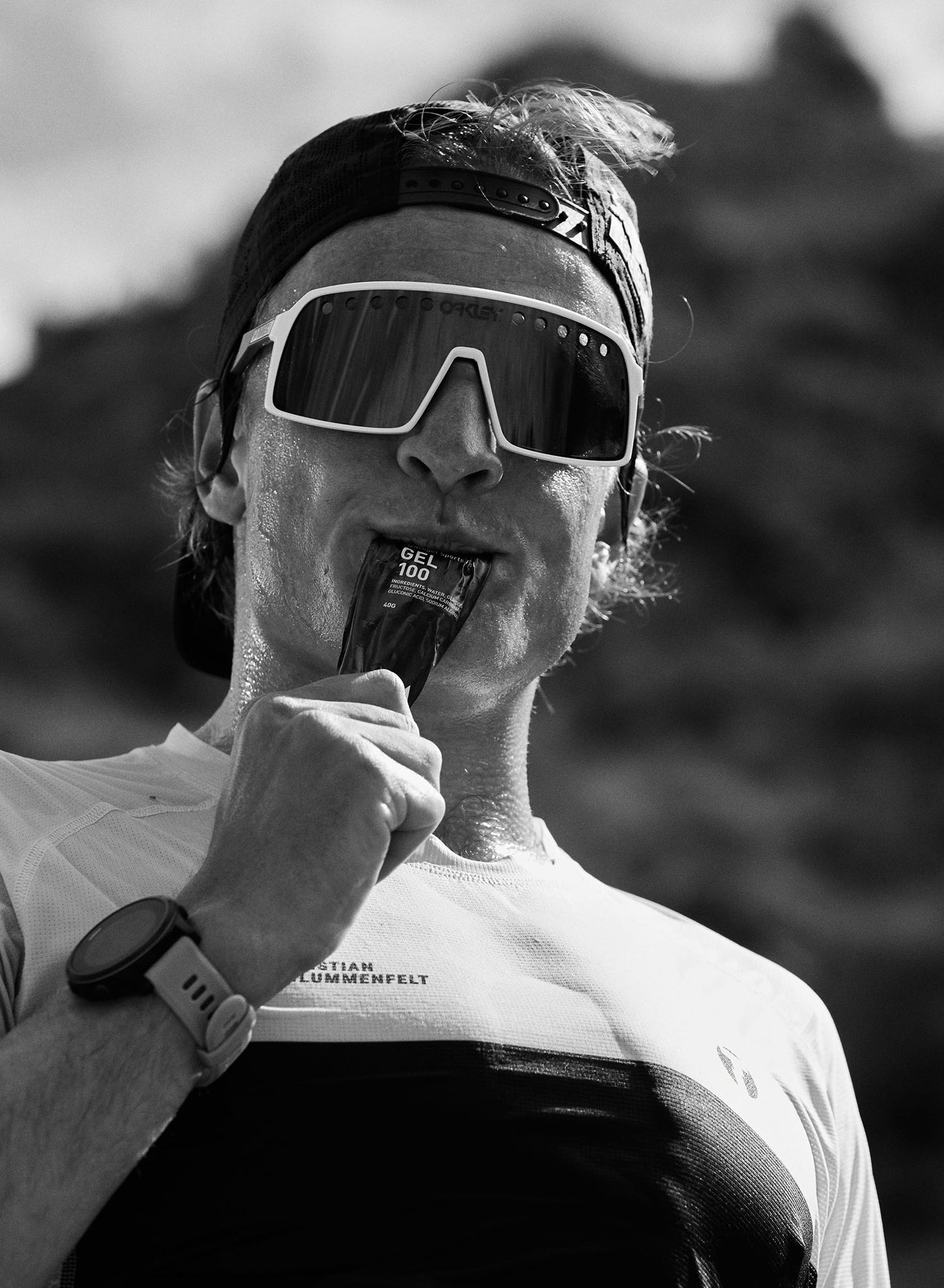 Male athlete wearing sunglasses and taking a Maurten Gel 100