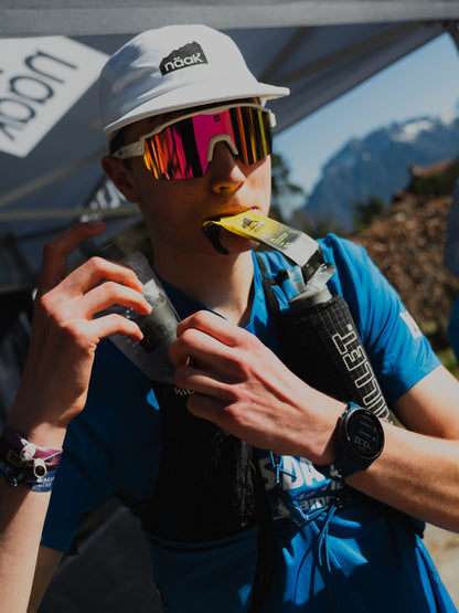 Ultra runner eating a Näak Boost gel packet and putting a bittle back in a hydration vest 