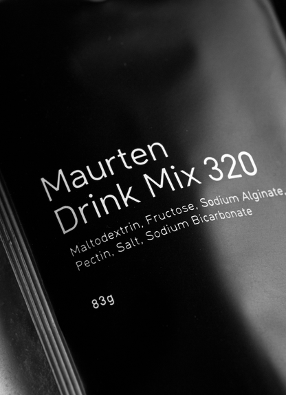 A close-up of a single packet of Maurten Fuel Drink Mix 320, primarily in black color with white text detailing the product name and ingredients.