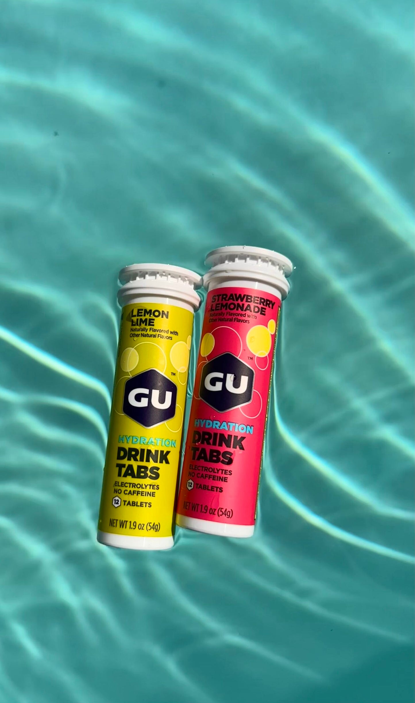 Lemon Lime and Strawberry Lemonade Gu Drink Tab canisters floating in pool water
