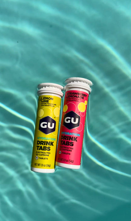 Lemon Lime and Strawberry Lemonade Gu Drink Tab canisters floating in pool water
