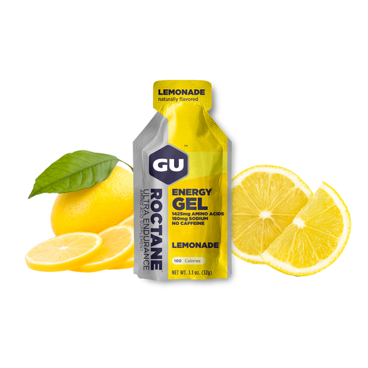 A packet of GU Roctane Energy Gel with lemonade flavor, accompanied by sliced lemons and a whole lemon on a white background.