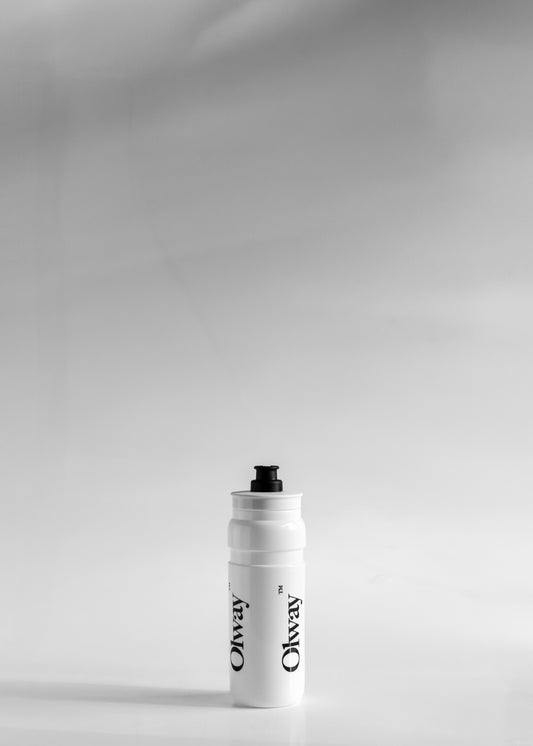 A white Oway water bottle with a black cap, standing upright on a light gray surface available at Fuel Kit.
